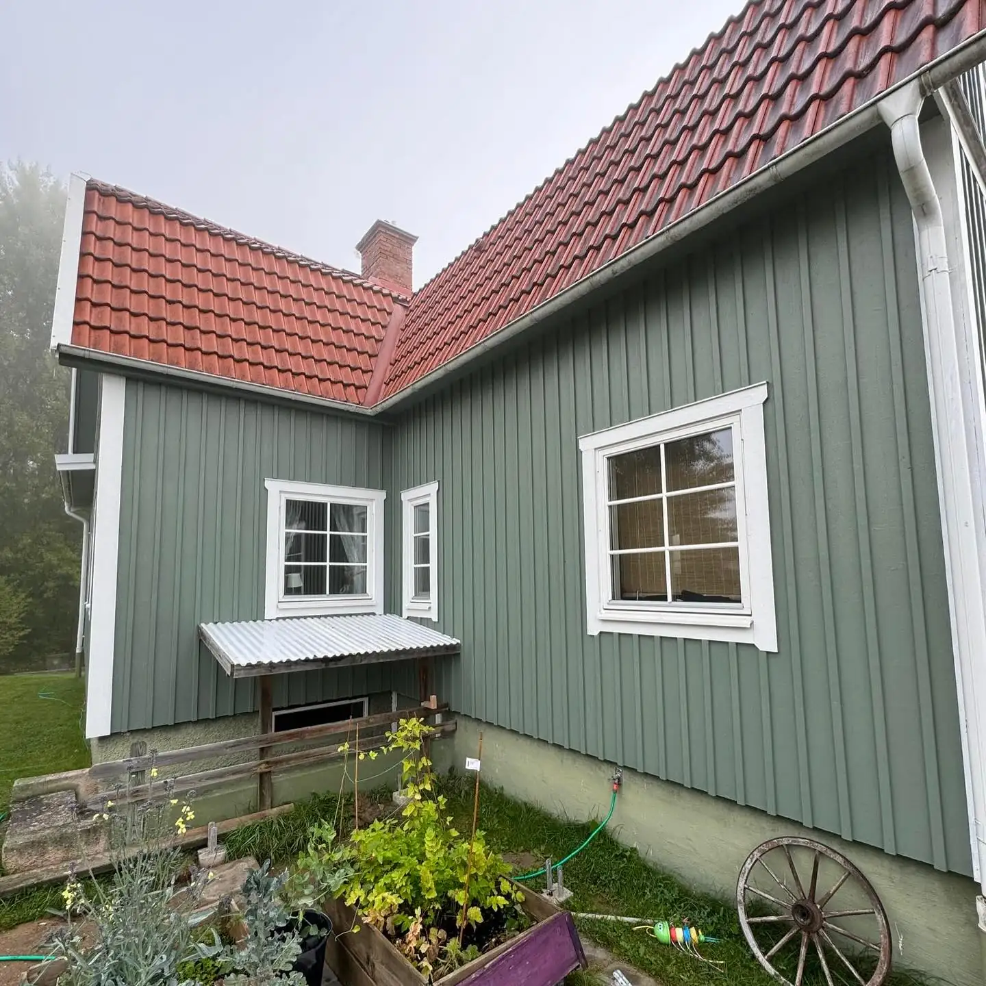 Nymålad grön fasad med vita knutar och fönster