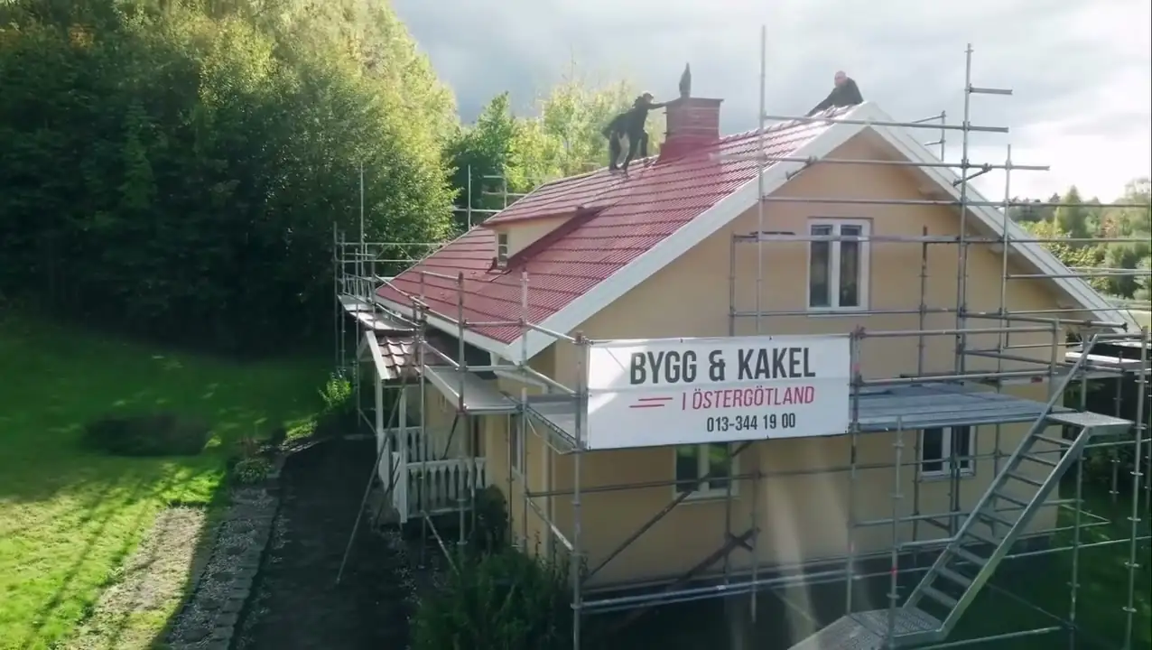 Hus med byggställning och Bygg & Kakel-skylt under takarbete